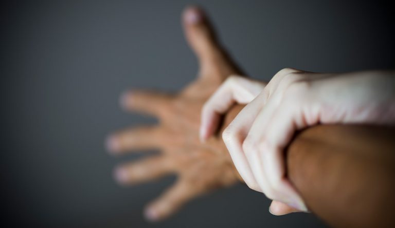 An image of a light skinned woman's hand holding the wrist of a darker-skinned male.