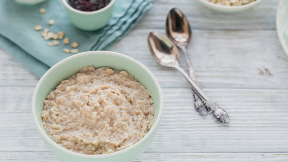Oatmeal porridge bowl with berry jam on the white wooden background. Healthy nutritious breakfast.