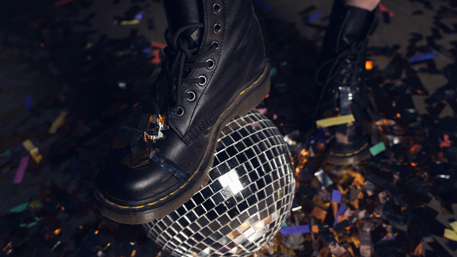 A photo of a floor filled with confetti, and a black leather boot sitting on top of a disco ball